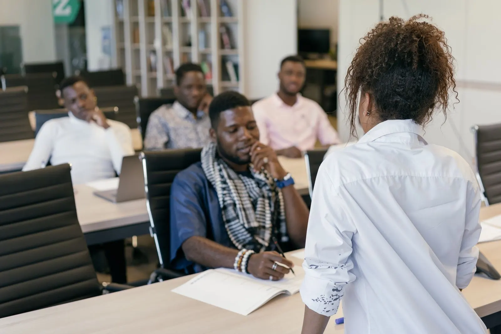 A facilitator leading a training session for a room of new colleagues taking notes