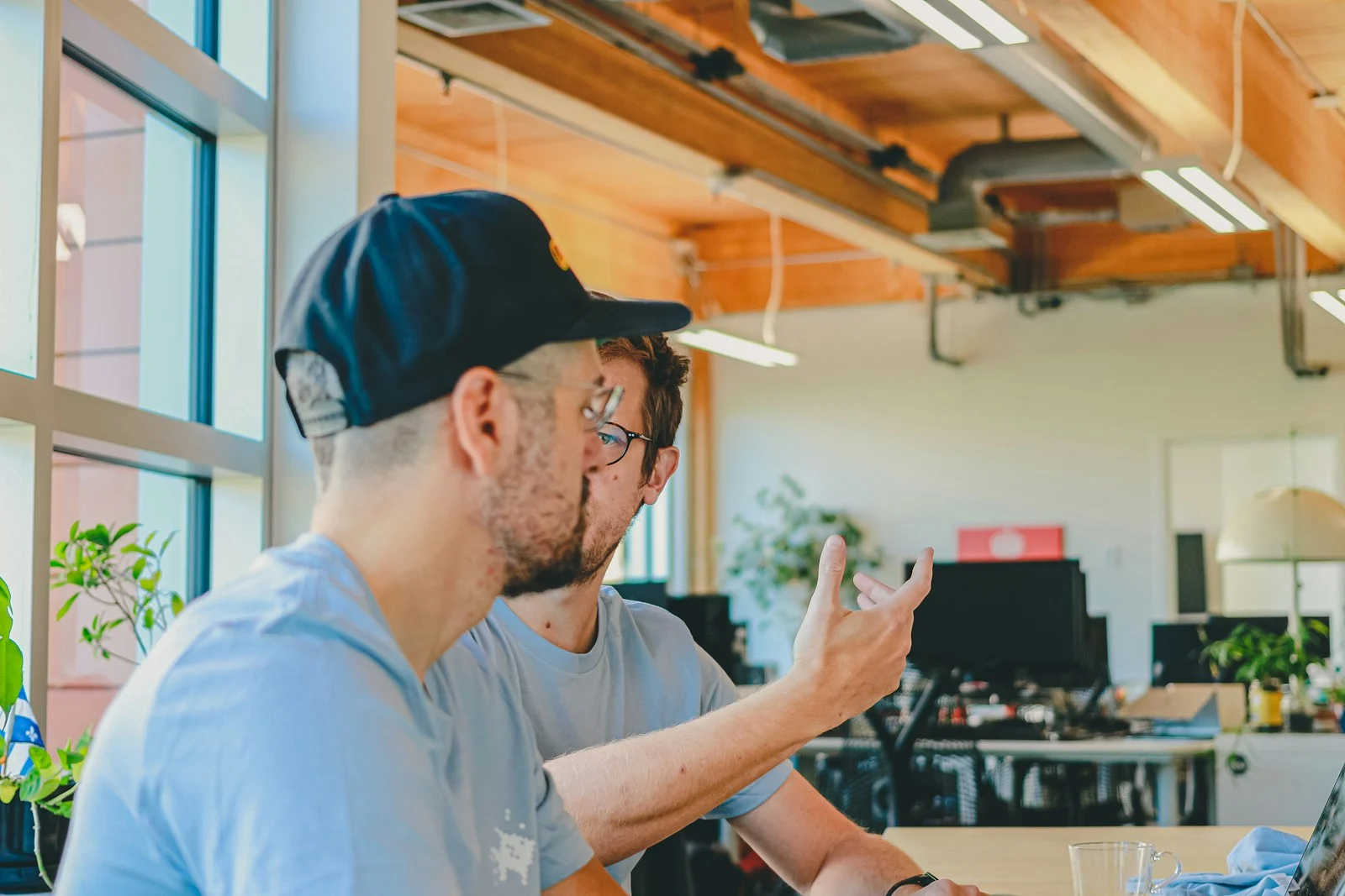 Two colleagues sharing an explanation at a workstation in an open office