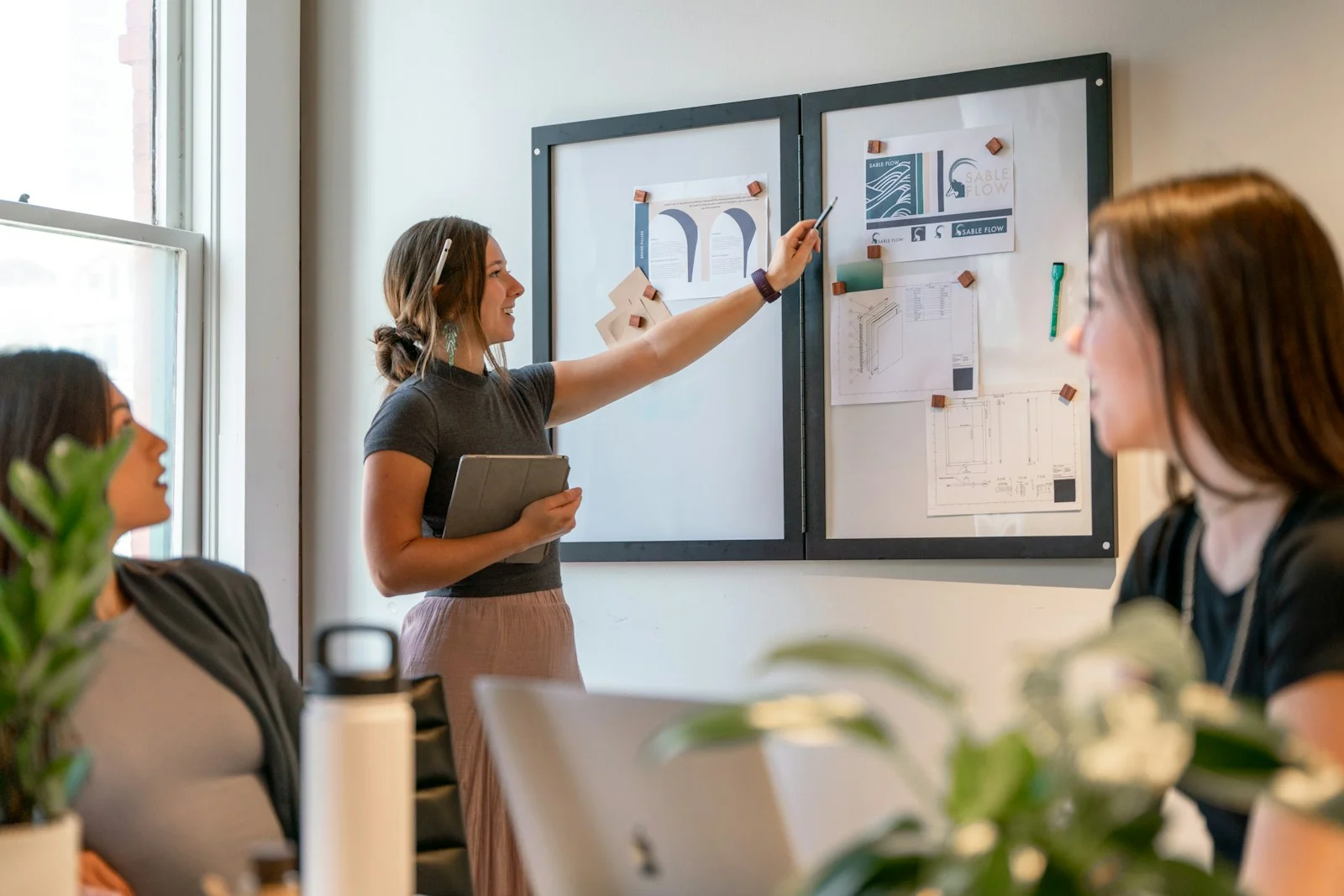 Women discussing project ideas and reviewing plans together at a presentation board