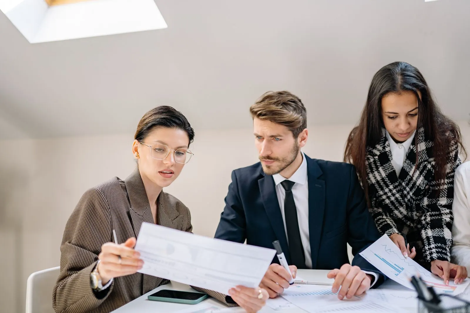 Three business leaders reviewing printed performance charts together at a meeting table